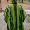 Back view of model wearing hooded green poncho with South American pattern