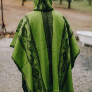 Back view of model wearing hooded green poncho with South American pattern, like Bruno's poncho