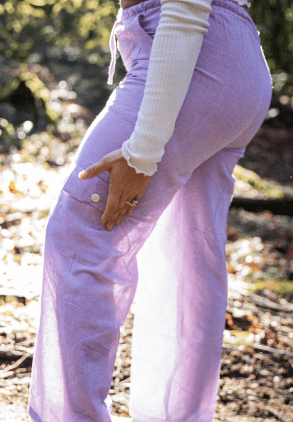 Side view of model wearing lavender harem pants with sunlight filtering thru them