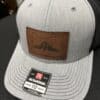 Front view of gray and black Richardson Trucker Hat with sewn-on leather patch with Oregon map and image of Mt Hood