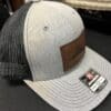 Side view of gray and black Richardson Trucker Hat with sewn-on leather patch with Oregon map and image of Mt Hood