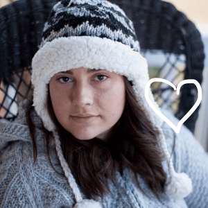 Young woman wearing handknit wool beanie lined with sherpa, with pompoms