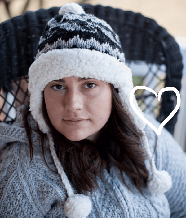 Young woman wearing handknit wool beanie lined with sherpa, with pompoms
