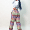 Back of female model wearing woven cotton pants with elastic waist and drawstring ankles, in orange, green and purple
