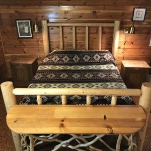 Brown and cream Southwestern design blanket on a log bed in a log cabin.