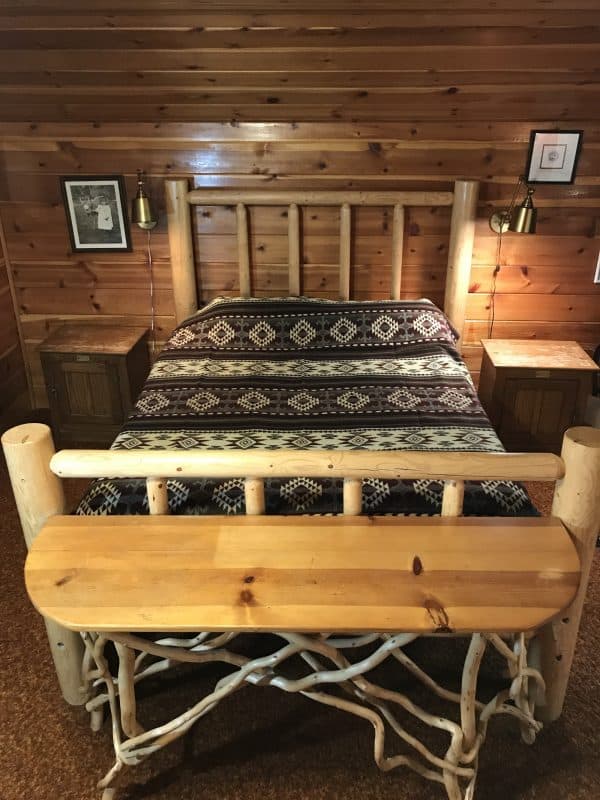 Brown and cream Southwestern design blanket on a log bed in a log cabin.
