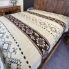 Cream blanket with Southwestern geometric design in dark brown on a dark wood bed