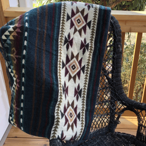 Southwestern pattern couch throw in green, burgundy, brown and cream tossed over black wicker rocker