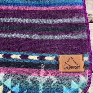 Southwestern pattern blanket in purple, blue and cream, folded in a closeup view