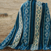 Model standing in field wrapped in Southwestern design blue, cream and turquoise blanket