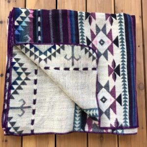 Southwestern pattern purple, turquoise and cream throw, folded to show reverse side on wooden floor