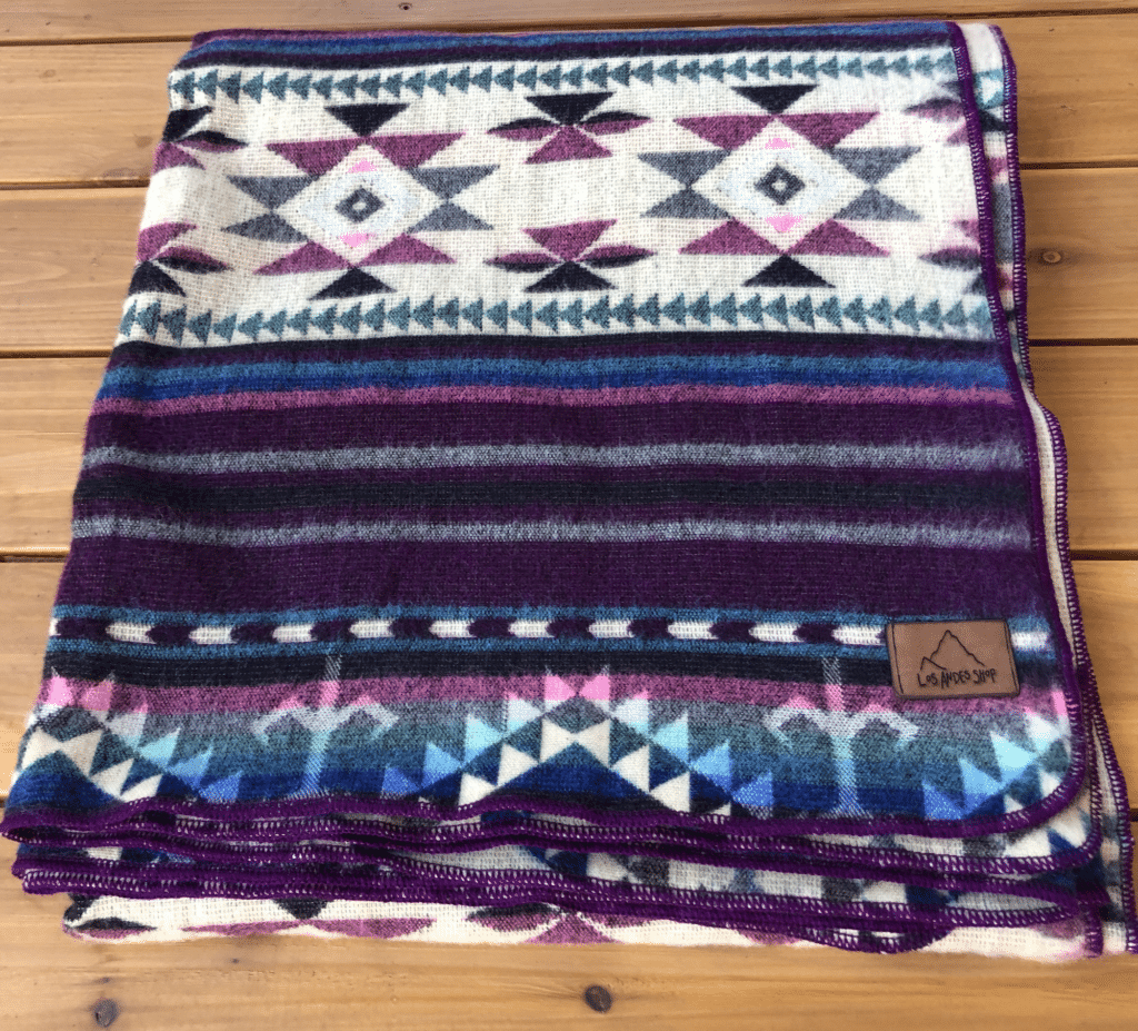 Purple and turquoise Southwestern queen size blanket, folded, on hardwood surface