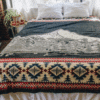 Medium Gray blanket with mountain image and geometric border displayed on a bed