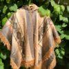 Gold poncho with South American pattern hanging in foliage