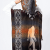Back view of model wearing hooded poncho in rust and brown with Bigfoot image on it