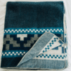 Turquoise and blue native queen blanket with Andean Cross design, corner folded back to show cream color reverse