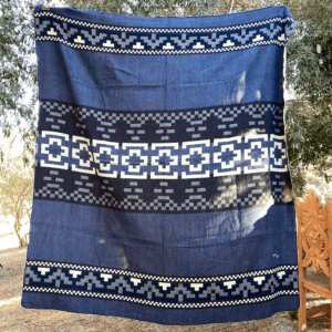 Queen size blue blanket with Andean Cross geometric design hanging outdoors from a line