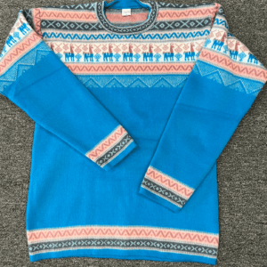 Sky blue crewneck sweater with pink black and cream design on yoke featuring llamas, laying flat on a gray surface
