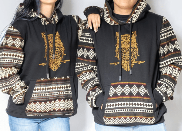 Male and female models wearing hoodies with gold machine-embroidered owl, black hoodie body, and geometric sleeves and kangaroo pocket.