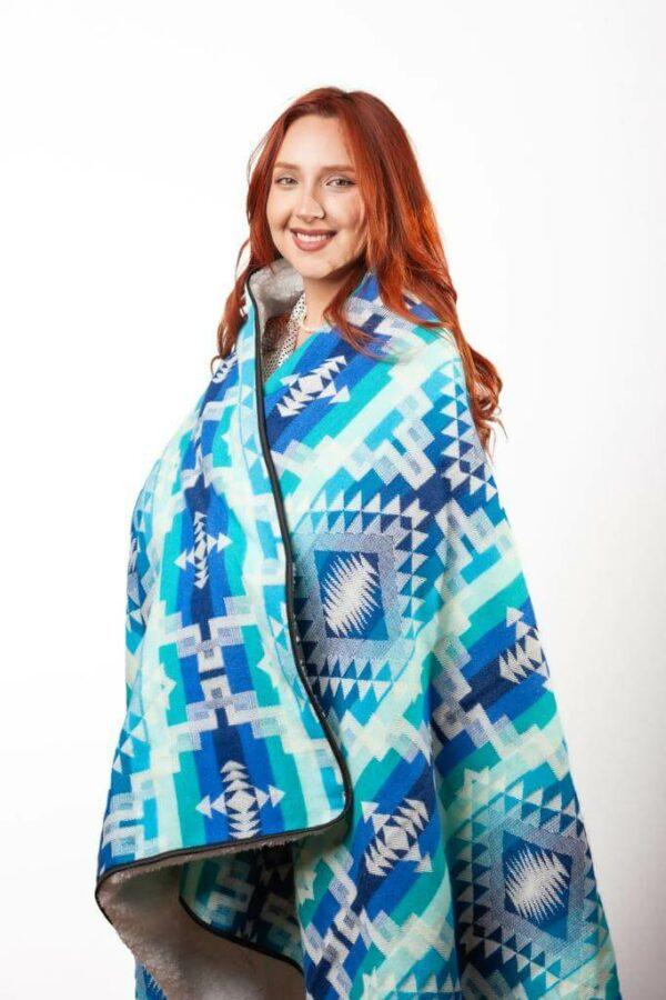 Redheaded smiling female model wearing blue and turquoise zip blanket poncho