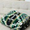 Green, black and gold blanket poncho folded on a couch