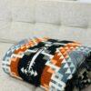 Orange, black and grey blanket poncho folded on couch