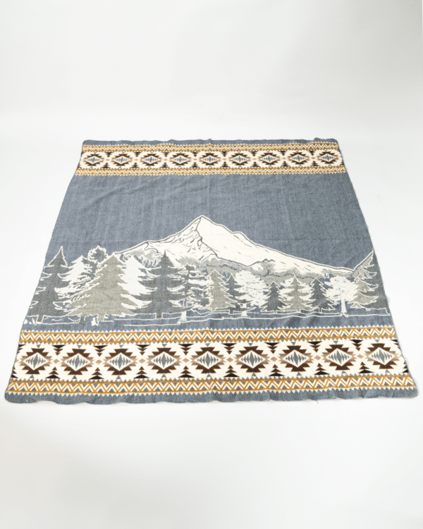Light gray blanket with image of Mt Hood and evergreens, geometric border in cream and brown across top and bottom edge