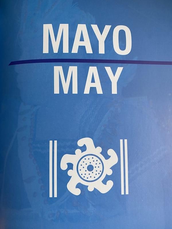 Words "mayo - may" and Incan symbol on blue background