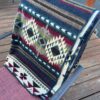 Southwestern design blanket in jewel tones folded on a patio chair