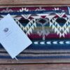 Jewel tone Southwestern design blanket, folded on wooden patio, with journal lying on top